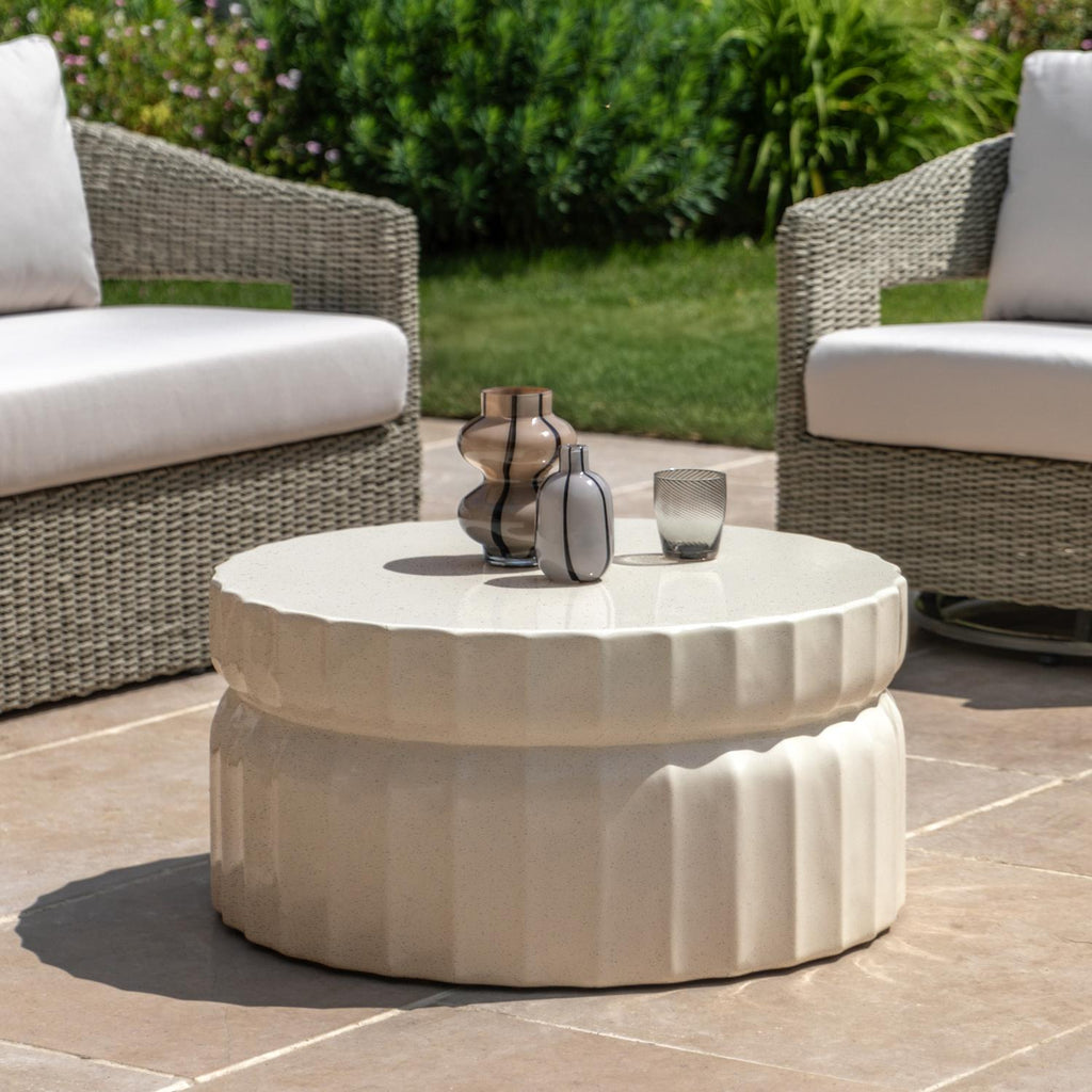 Round outdoor coffee table with decorative items in a patio setting