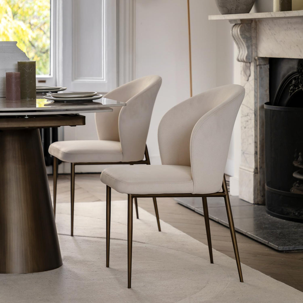 Dining room with a table and two beige chairs in front of a fireplace.
