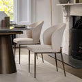 Dining room with a table and two beige chairs in front of a fireplace.