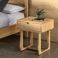 Wooden bedside table with a plant and book next to a bed