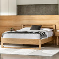 Wooden bed with white bedding and a gray pillow in a modern bedroom setting.