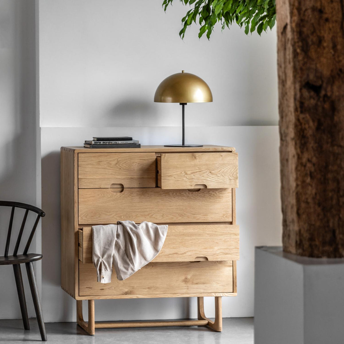 Wooden dresser with open drawer in a room with a lamp and chair.