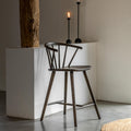 Wooden bar stool in a minimalistic room with a white counter and decorative elements.