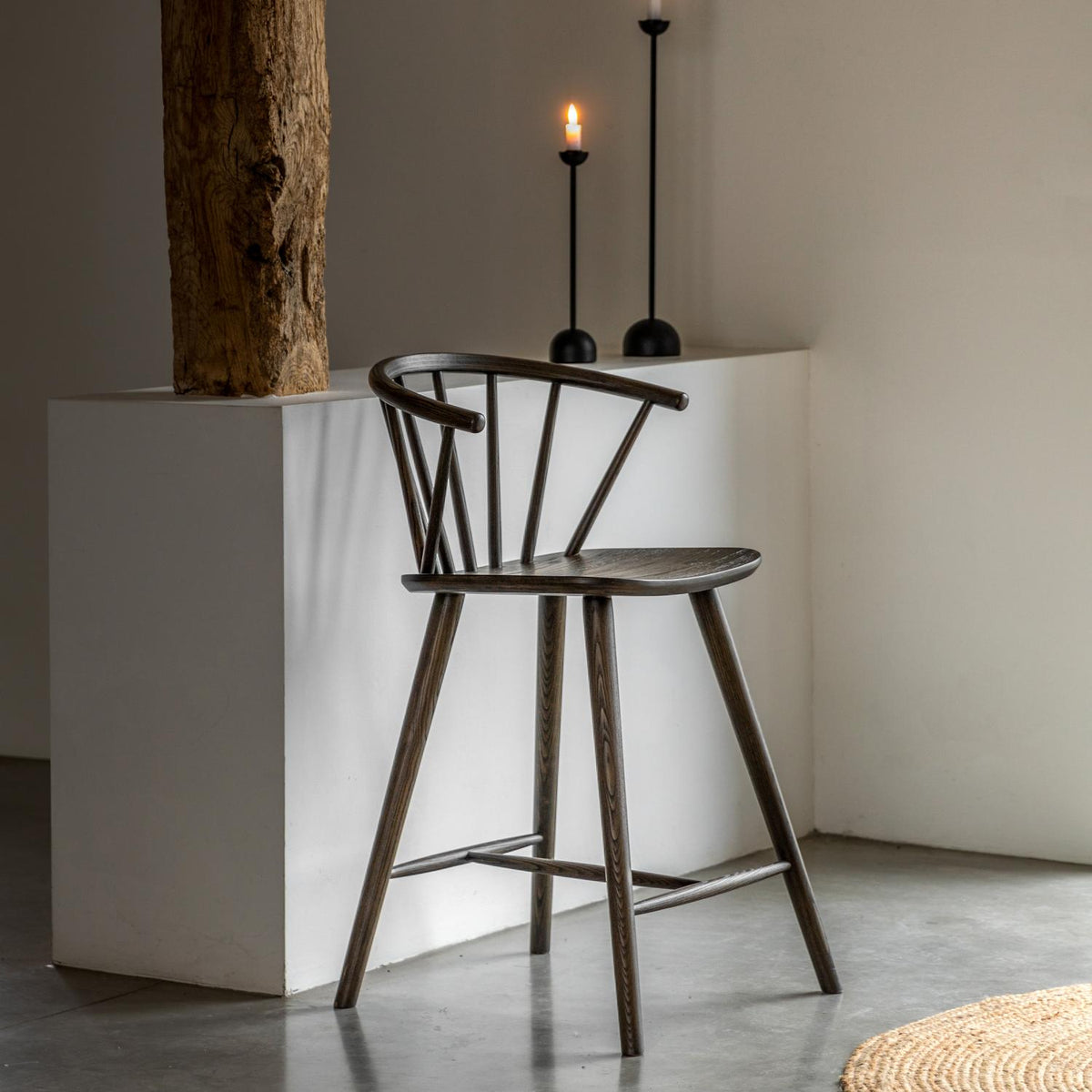 Wooden bar stool in a minimalistic room with a white counter and decorative elements.