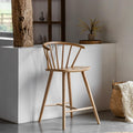 Wooden bar stool in a modern interior setting with a white counter and decorative items.