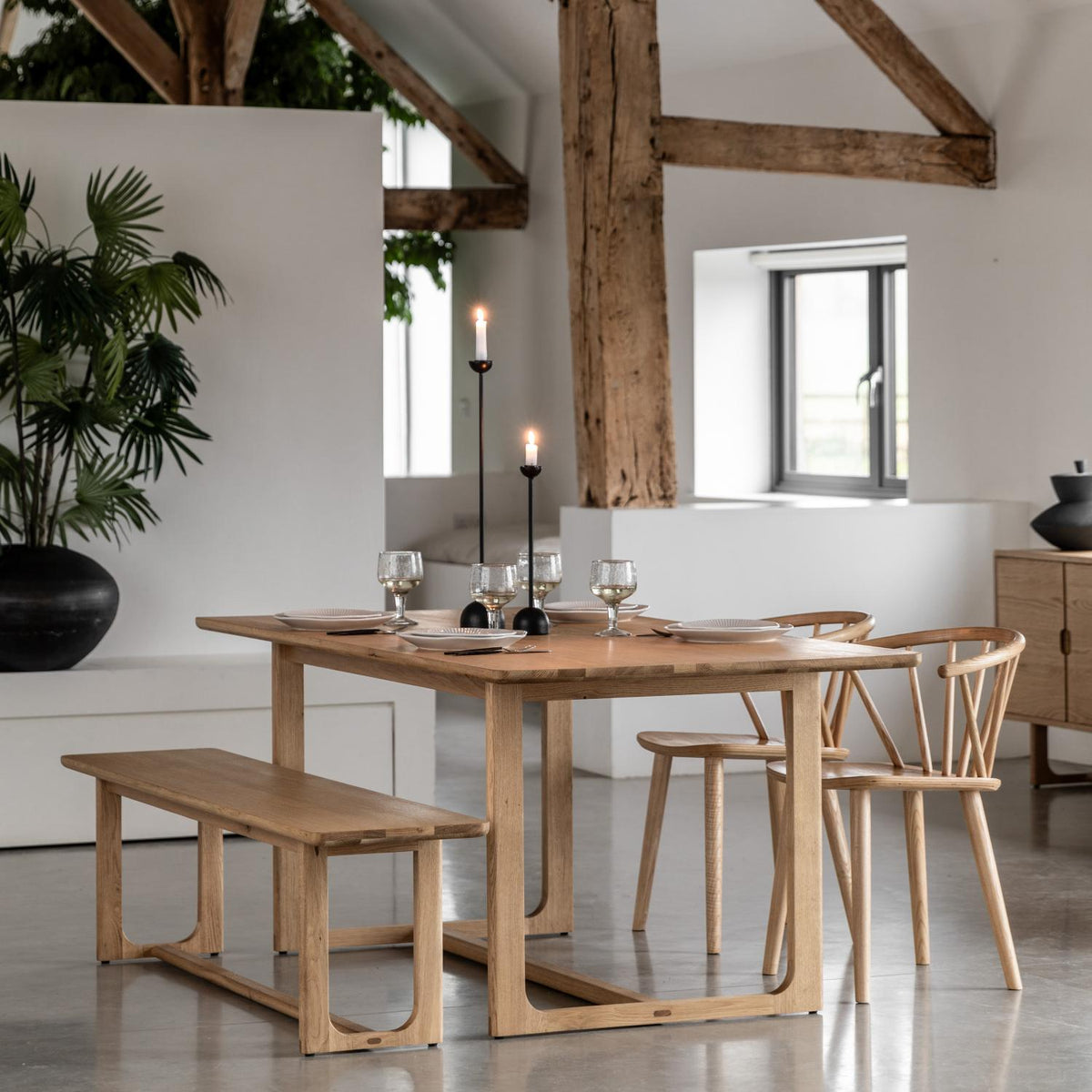 Dining area with wooden table, chairs, and bench in a modern interior setting.