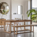 Dining room with wooden table, chairs, and bench in a bright room.