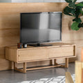 Wooden TV stand with a television on it against a wooden wall.
