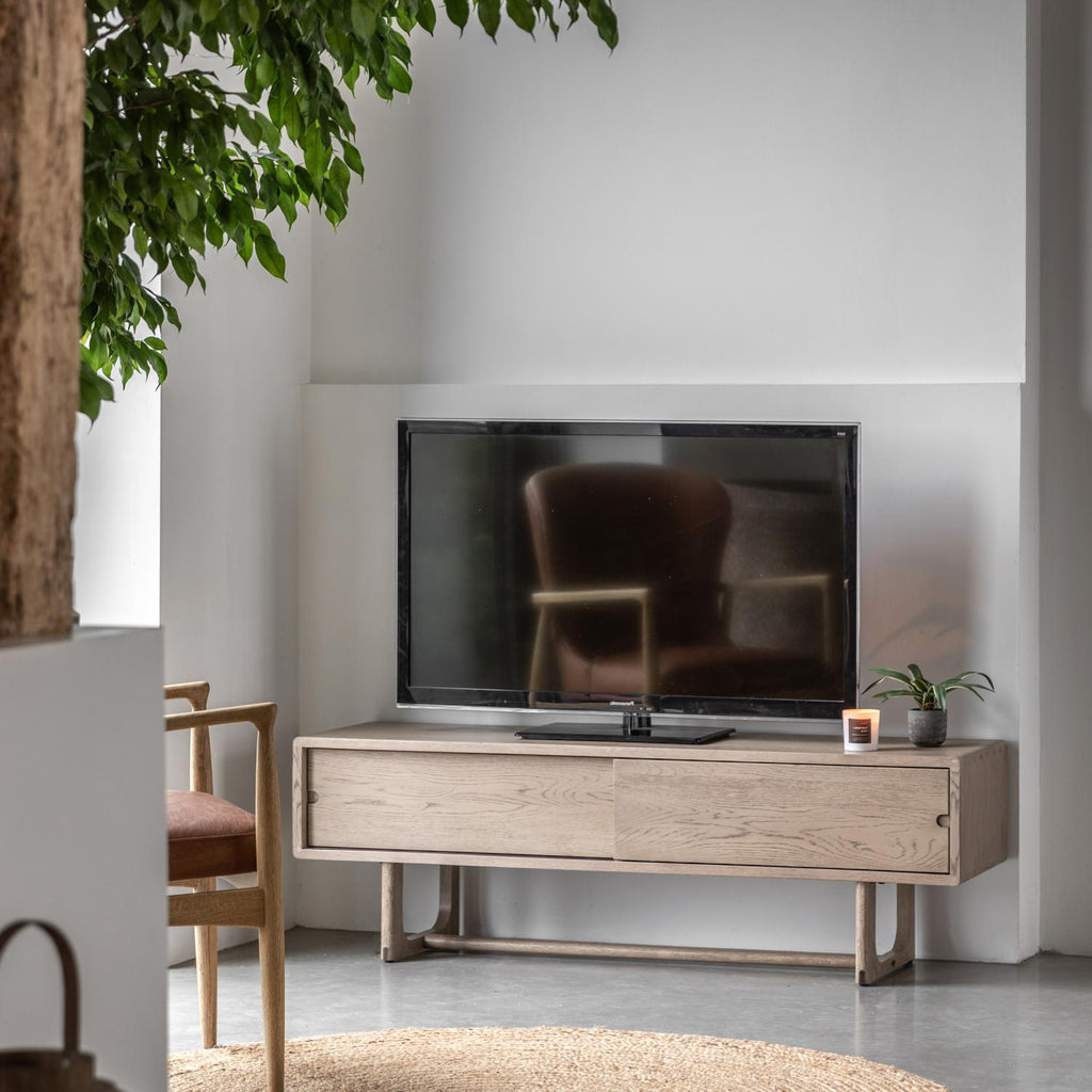 Modern living room with a television on a wooden stand, surrounded by minimal decor.
