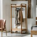 Wooden clothing rack with clothes in a room setting