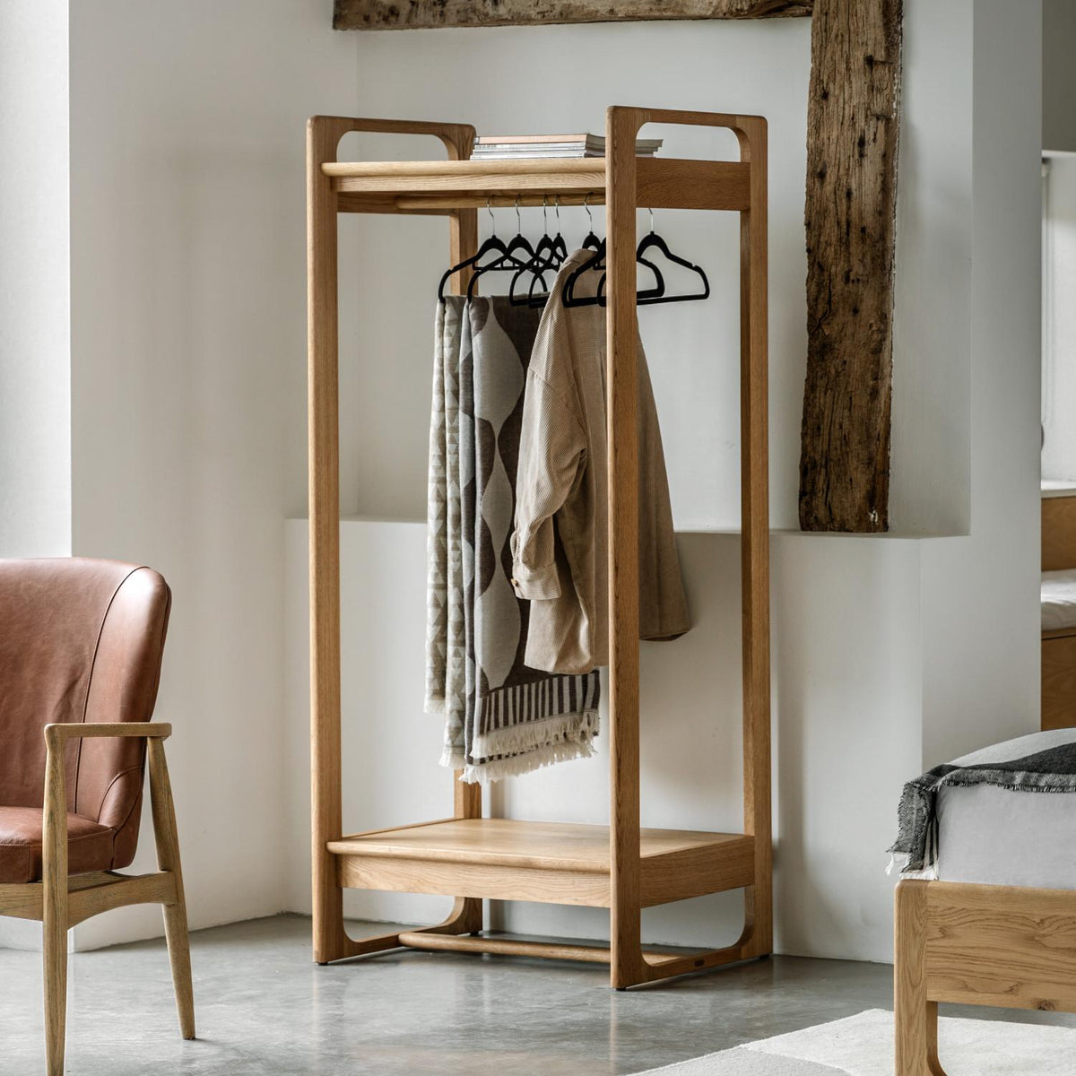 Wooden clothing rack with clothes in a room setting