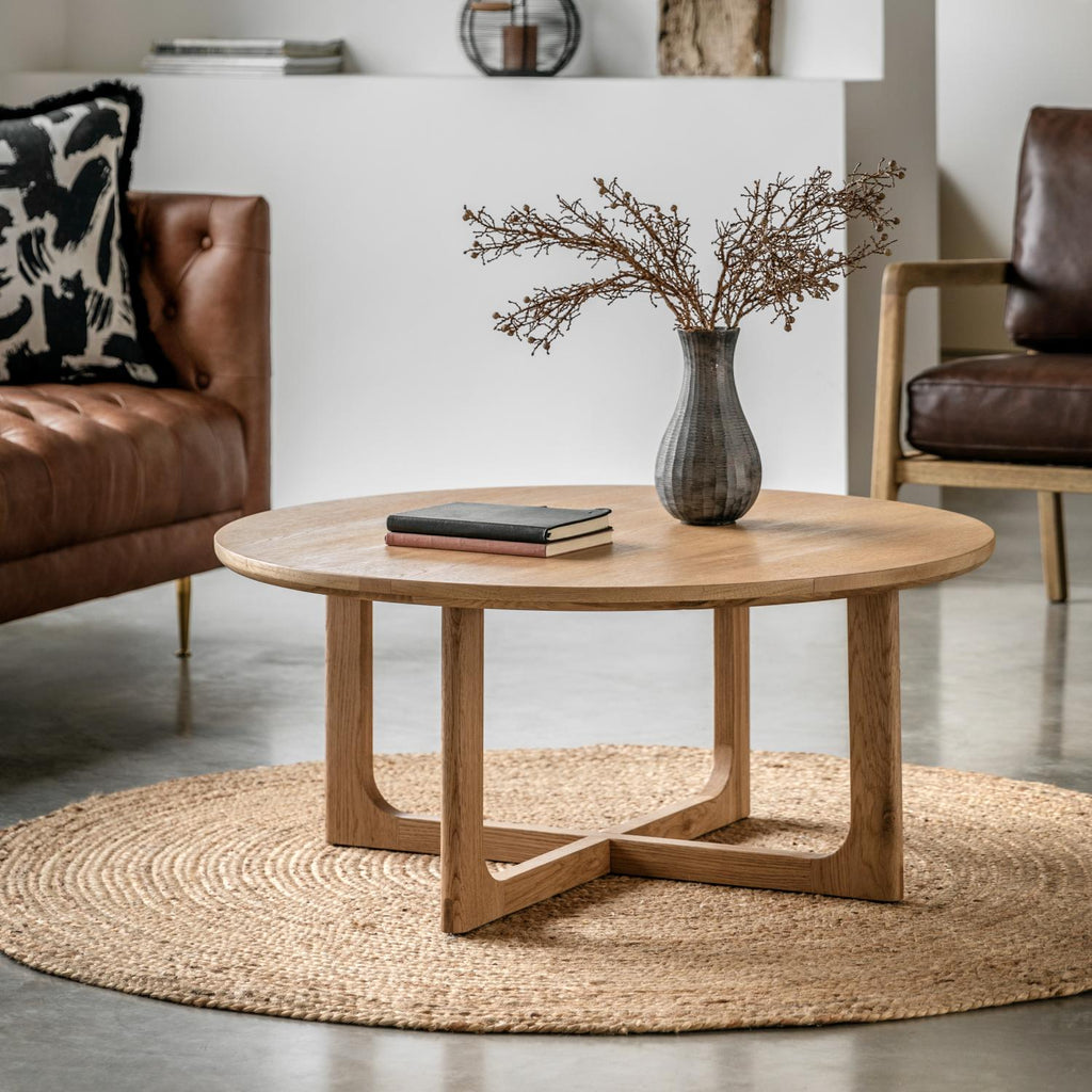 Wooden coffee table with a vase and books in a living room setting.