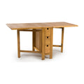 A light oak drop-leaf table with three drawers on the right side, shown on a clean white background.