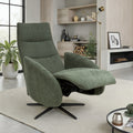 A modern sage green upholstered recliner chair with a black swivel base, shown in a styled living room setting with a rug, shelving, and plants.
