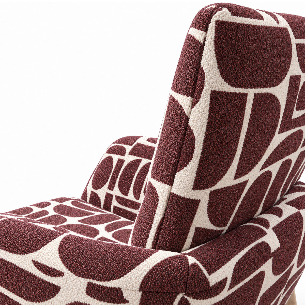 Close-up of the curved back and armrest of the Sloane dining chair in plum geometric pattern fabric