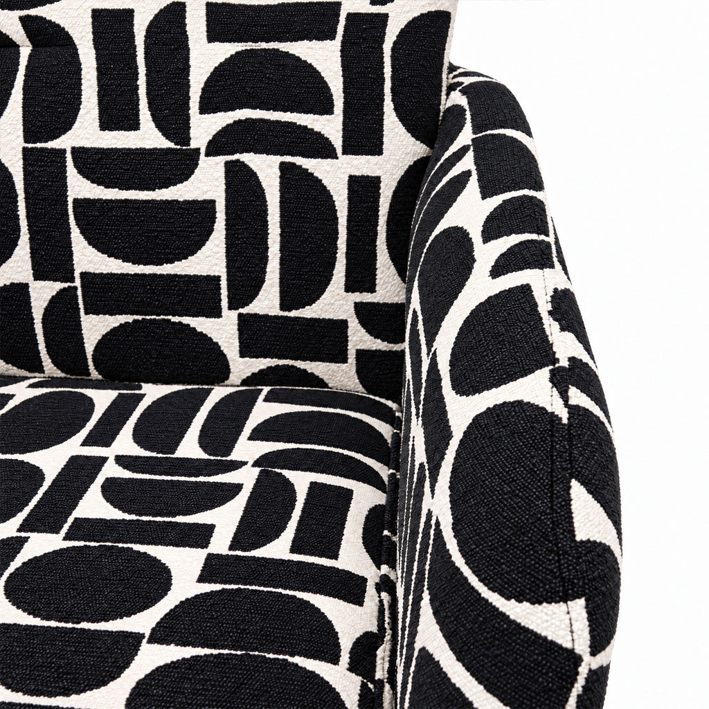 Close-up of the cushioned seat and arm of the Sloane dining chair in black geometric pattern fabric