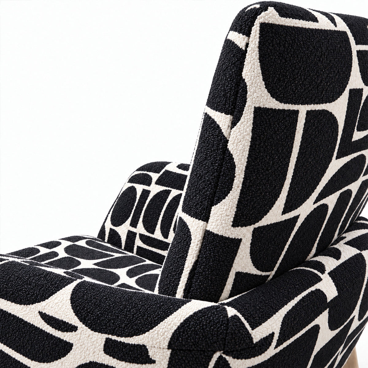 Close-up of the curved back and armrest of the Sloane dining chair in black geometric pattern fabric