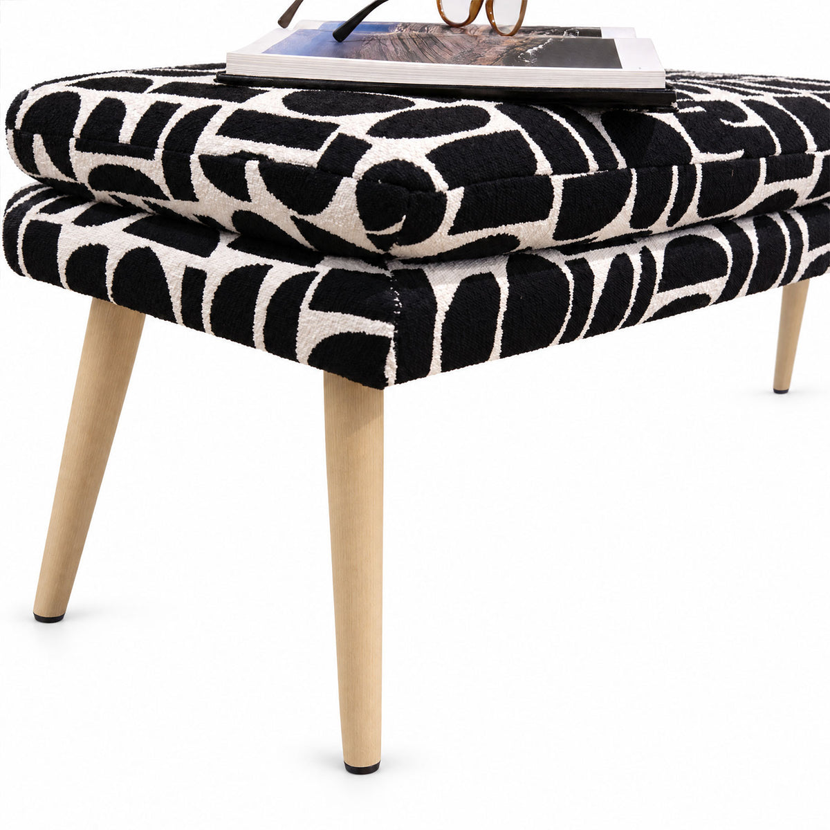 Close-up of the Sloane flat bench end and tapered wooden leg in black geometric pattern fabric