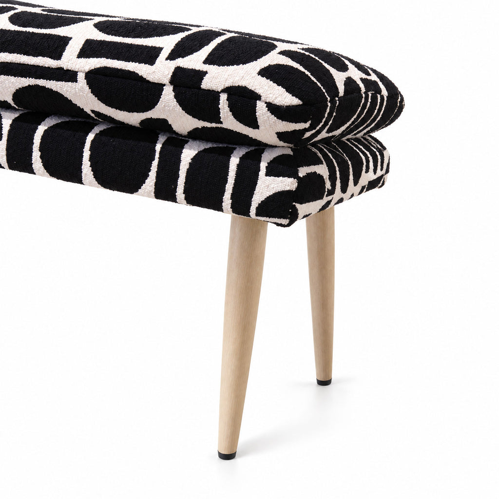 Side detail of the Sloane flat bench cushion and leg in black geometric pattern fabric