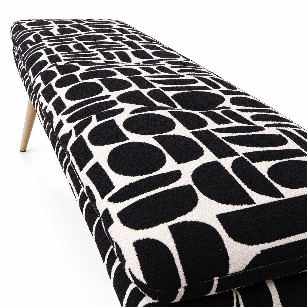 Close-up of the tufted seat of the Sloane flat bench in black geometric pattern fabric