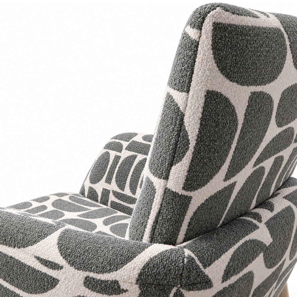 Close-up of the curved back and armrest of the Sloane dining chair in sage geometric pattern fabric