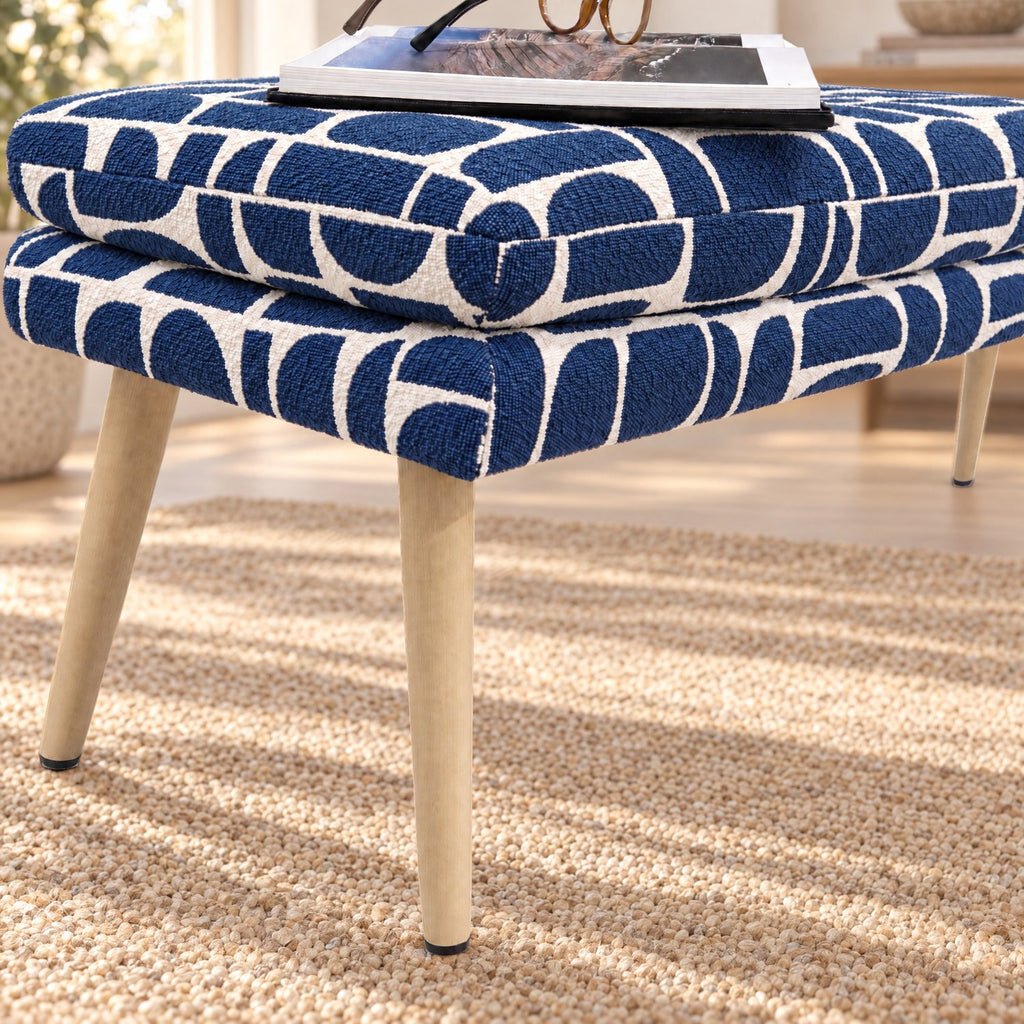 Close-up of the layered tufted cushion and beech-wrapped metal leg on the Sloane flat bench in blue